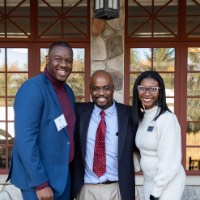 Quincy Williams poses with 2 other people outside the Alumni House